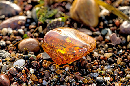 在波罗的海的海滩上安珀果汁岩石地质学材料橙子宝石化石康复宏观水晶背景图片