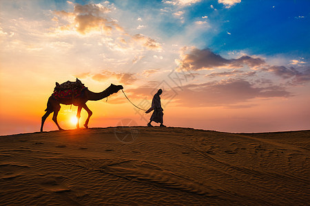 印度骆驼骑手在黄日夕阳沙丘带骆驼轮 印度拉贾斯坦邦Jaisalmer风景旅行晴天沙丘阳光沙漠男人太阳大篷车旅游图片