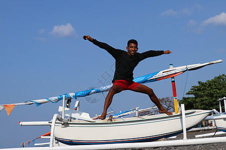 快乐的印尼年轻人在沙滩上跳跃 一个心情不错的少年腾空而起 与蓝天的晴朗的热带天天堂热带旅行海岸太阳支撑海洋假期天空风景图片