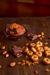 在一张木桌上的巧克力玛芬用巧克力和塔塔里尼坚果奶制品大麦盘子产品木板杏仁作品清洁葡萄干背景图片