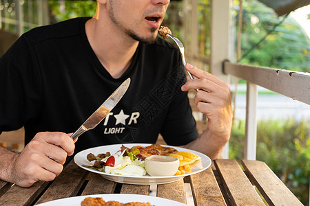 在夏日咖啡厅的餐桌上吃牛排的家伙牛肉盘子桌子猪肉商业食物饮食牛扒美食男性图片