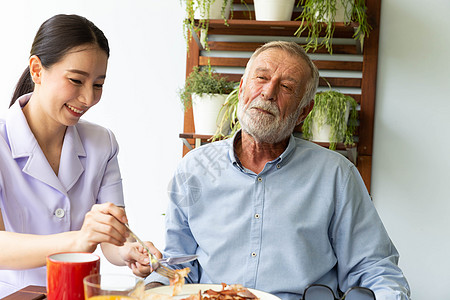 亚洲护士协助快乐的老年退休男子吃早饭 为他们提供帮助图片