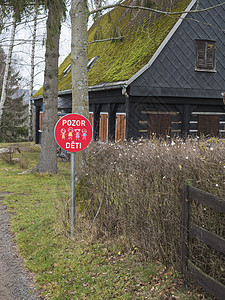 捷克标志带有捷克文字的红色交通标志 在带苔藓屋顶的木屋前注意儿童背景