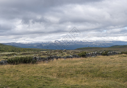 从挪威 E6 主干道出发 在自然公园欣赏山丘和雪山的秋景 云彩壮观顶峰闲暇远足森林戏剧性高地天空项目岩石荒野图片