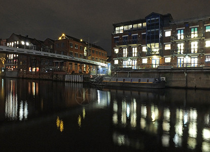 夜间在河上停靠 背着旧古老建筑和公寓的灯光照耀在水中 并有一艘停泊的驳船图片