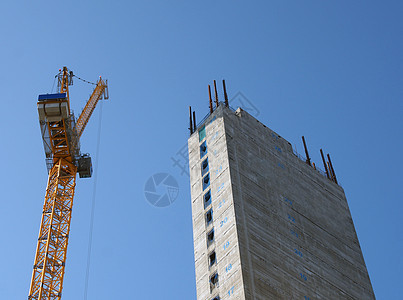 一座黄色高塔起重机 在建筑工地施工 用高高的混凝土塔对准明蓝天空图片