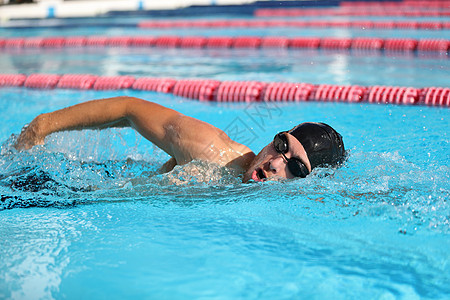 游泳比赛游泳运动员在游泳池里做爬行行程 男子游泳运动员戴着护目镜和呼吸帽在室内体育场比赛 速度锻炼锻炼图片