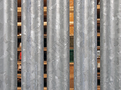 特写垂直镀锌钢栅栏 在隔缝之间可以看到户外储存的木质货盘图片