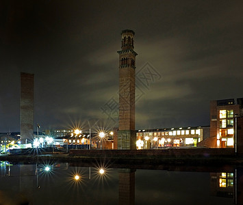 南边的霍尔贝克市风景显示 历史塔在夜间施工 办公楼和运河中的灯光都反映在河道上图片