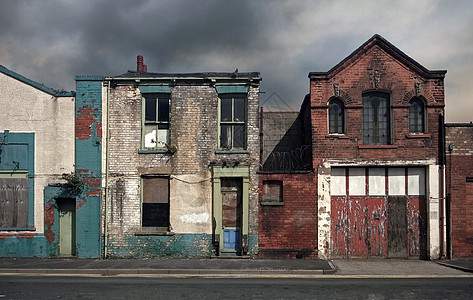 废弃的被遗弃房屋和建筑在荒无人居住的街道上 窗户被堵住 墙壁倒塌 对着一片灰色的云天空;图片