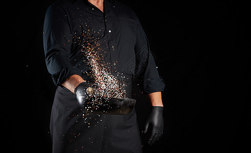 身穿黑色制服的男子 拿着一个带盐的圆面铁锅男人男性行动食物飞溅美食成人工具烹饪厨师图片