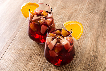 红葡萄酒甜点 在木制桌上的玻璃杯中投手橙子水果红色液体酒精热带柠檬玻璃饮料图片