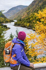 女徒步旅行者远足 欣赏秋叶山景的美景 秋季自然徒步旅行期间 户外冒险旅行的人站在河边放松夹克野营公园成人远足者树木踪迹瓶子树叶幸图片