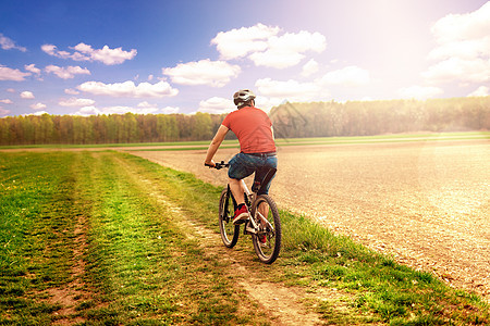 骑自行车 骑自行车 在公园里 在后面的树林里有草运动锻炼踪迹骑士男人活动旅行街道娱乐耀斑图片