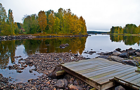 芬兰Kuhmo市附近的一个湖石头支撑木头风景反射松树森林蓝色全景天空图片