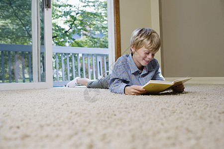 躺在地毯阅读书上的小男孩56岁孩子阅读房子男生地毯露齿短发一人快乐头发图片