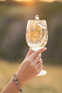 日落时 女孩在杯子里喝葡萄酒图片