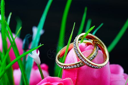 在假粉红色郁金香花中休息的结婚戒指婚礼乐队火花首饰奢华订婚新娘礼物金子钻戒图片