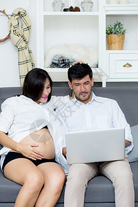 一对年轻的亚裔夫妇的肖像 夫妻坐在一起技术婴儿腹部怀孕成人笔记本父母电脑女性男人图片