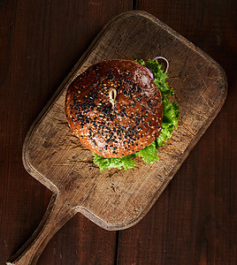 美味的汉堡和芝麻面包 在旧棕色切面板上营养沙拉午餐美食洋葱食物木头小吃芝士烧烤图片