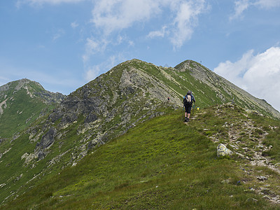 西塔特拉山脉或 Rohace 的美丽山景 男子徒步旅行者在山脊上背着背包远足小径 锋利的绿草如茵的落基山峰 夏天蓝天白云图片