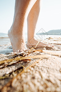 在阳光明媚的一天 在海滩水中 女人脚踏在海边的水里图片