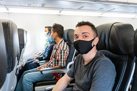 飞机乘客脸上戴着医疗面罩 AiAi男人感染男性旅行旅游运输飞机场流感空气假期图片