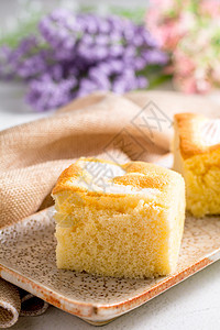 盘子和白桌子上一块平方椰子蛋糕黄色白色甜点香草蓝色糕点面包美食食物海绵图片