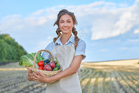 女农民围裙站在农田微笑天空收获生态女性土地收成农业沙拉黄瓜蔬菜图片