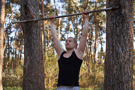 英俊的白人男子引体向上户外锻炼交叉训练早晨抽气手臂锻炼运动场自然森林公园身体健美成人运动员运动行动单杠男性力量图片
