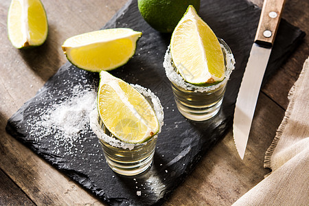 墨西哥的金龙舌兰酒 木制桌上有石灰和盐饮料水果金子玻璃酒精桌子液体图片