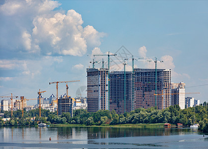 在Dnipro河岸沿线建造现代住宅高楼建筑 塔吊车向上攀升 直达云层的高度图片