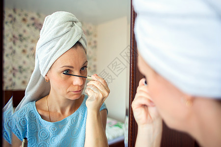 早上在卧室化妆时 女人用毛巾洗头 在浴巾里化妆 女孩用马斯卡拉涂眼粉眼睛仪式衣柜头巾工作费头发睫毛厕所睫毛膏脸颊图片