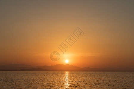 美丽的日落在地平线上海岸海滩海浪反射海洋日出橙子黄色天空太阳图片