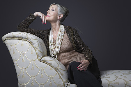 在Chaise休息厅的富贵高龄妇女座椅财富耳坠黑色魅力背景项链珍珠空闲成人图片