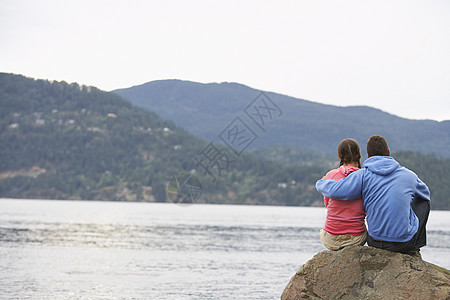 坐在海边岩石上的一对情侣风景休闲假期夫妻服装团结微笑女性中年两个人图片