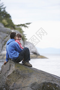 坐在海边岩石上的一对情侣男子成人微笑大海夫妻场景男人中年享受休闲图片