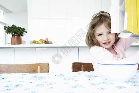 女孩(5-6)坐在桌边 面碗和一盒谷物图片