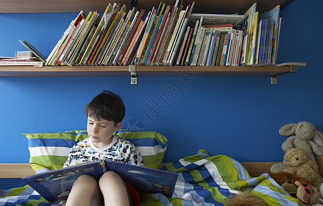 坐在床上阅读书上的男孩(5-6)图片