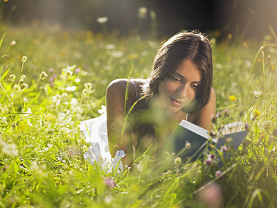 躺在草地阅读书中的年轻妇女女性微笑成年一人休闲美丽头发样子福利阳光图片