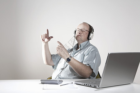 手持耳机的商务人士在办公桌休息娱乐男人眼镜音乐沉思影棚笔记本电脑商务秃顶图片