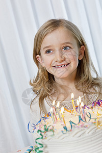 快乐的年轻女孩在生日蛋糕上用蜡烛烧掉图片