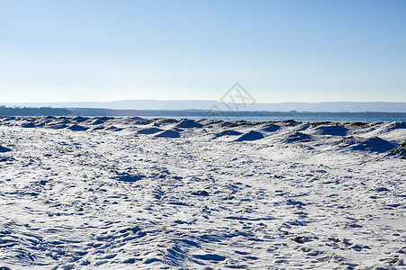 冷冻的冰雪和沙丘 在海滩上与远处的山丘图片