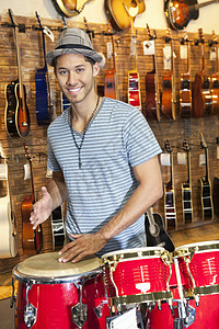 一个快乐的人在音乐店里打鼓的肖像男性帽子服装乐器幸福电吉他购物休闲成人棕榈图片