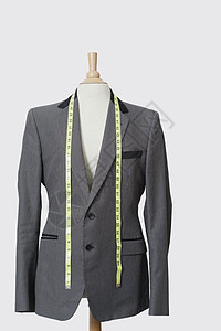 穿着灰色背景的测量胶带的裁缝假衣服西装正装产业商业彩色制造业男装设计纺织生意图片