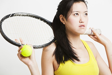 怀着深思熟虑的年轻女子 拿着网球拍打和白底球图片