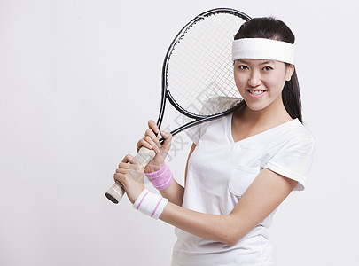 快乐的女性网球运动员在白人背景下握着电击的肖像图片