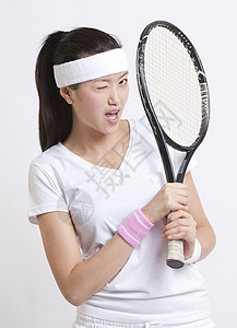 白种背景的网球拍打眨眼的亚洲年轻女性肖像图片