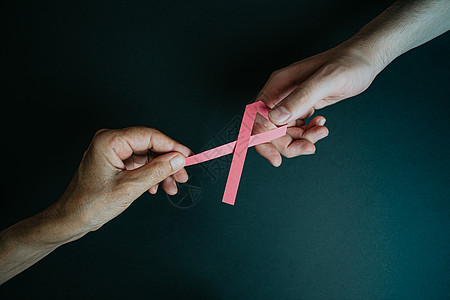 一只老手把粉红丝带给一只年轻的手女性治愈检测癌症生存胸部健康世界疾病机构图片