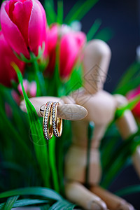持有两枚金婚戒指的木人图宏观首饰钻石钻戒念日金子婚姻粉红色火花礼物图片